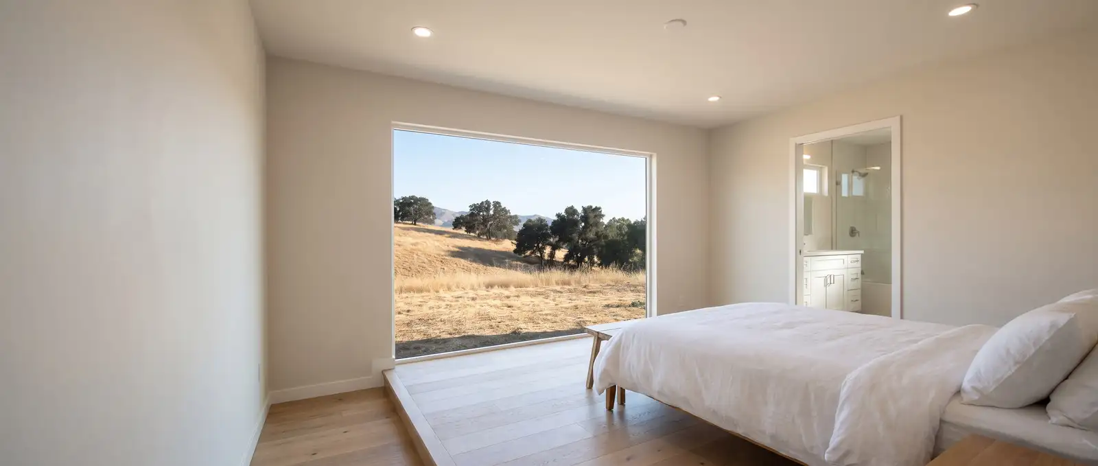 Garaje de dos carros convertido en recámara con una ventana ancha donde estaba el portón, piso de roble y una cama tendida, ilustración generada con IA